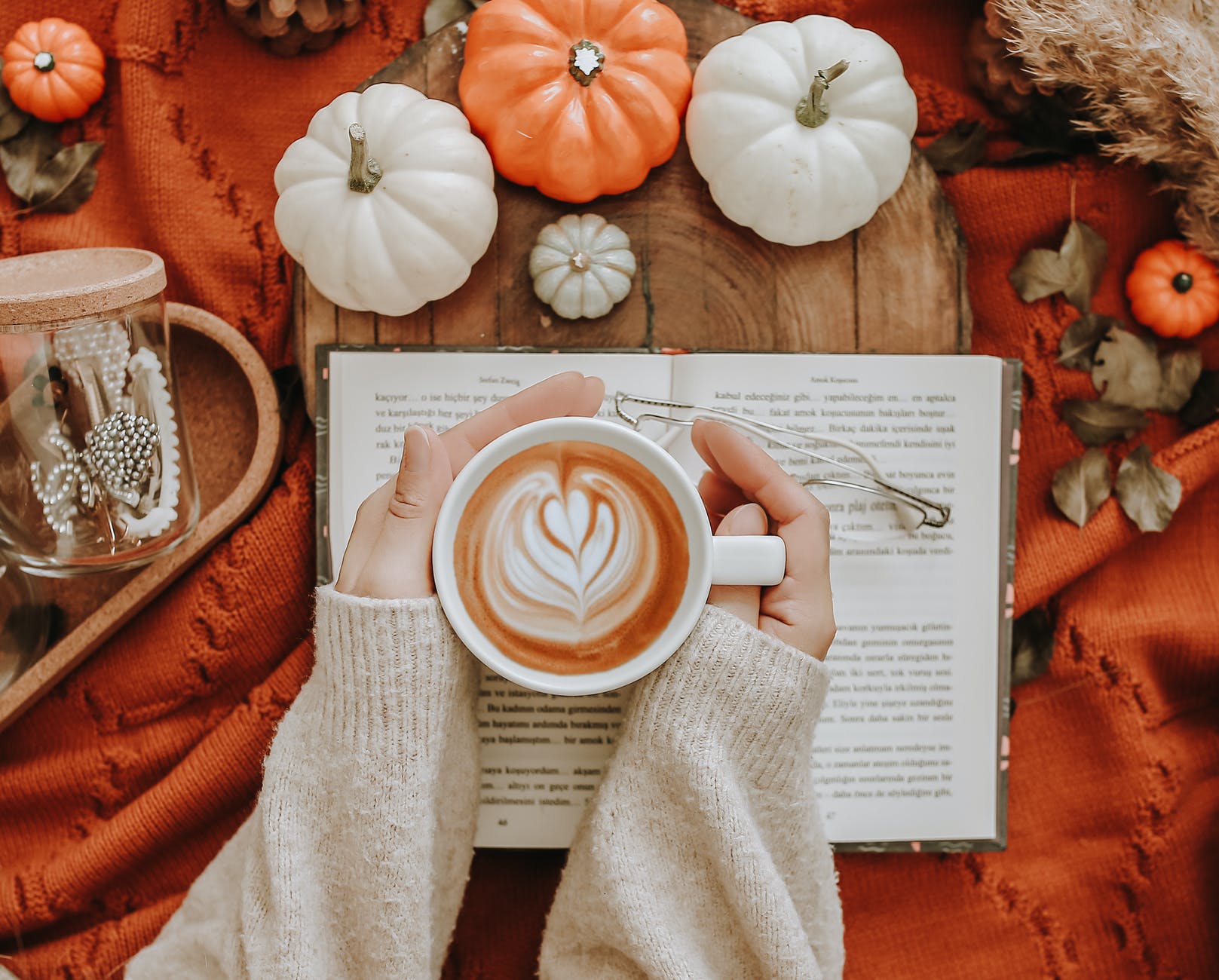 anonymous woman with coffee near pumpkins