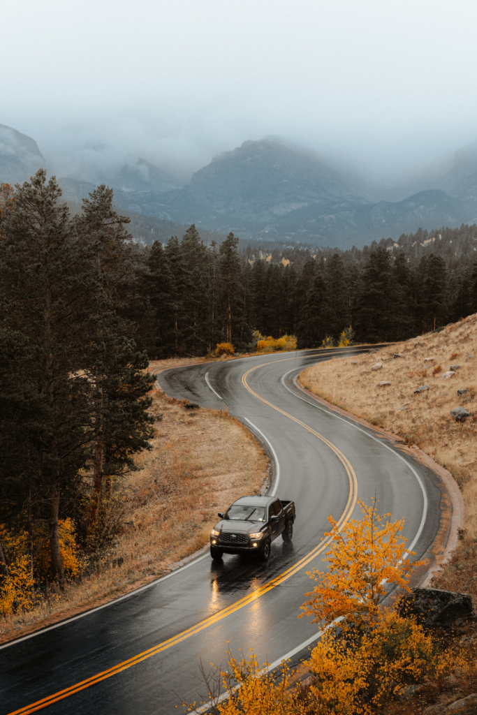 Car driving through fall foliage road
