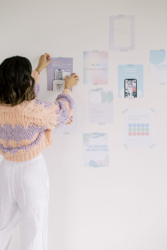 woman putting photos on a wall as an example of The Power Of Vision Boards